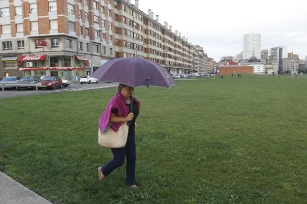 Los paraguas volvieron a salir ayer a la calle. En la imagen, una mujer en el 'solarón'. 
