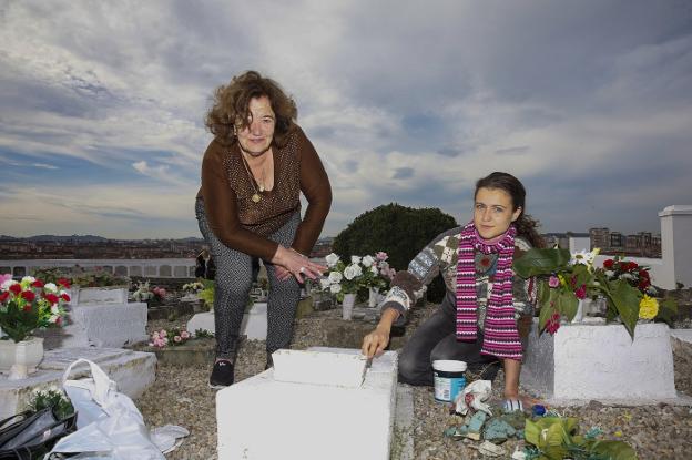 María Isolina Infanzón y su nieta, Lidia Méndez, en la zona donde están enterrados los niños en el cementerio de Ceares-El Sucu. Abuela y nieta enyesan la tumba del pequeño Isidrín, fallecido hace treinta años durante el parto. 