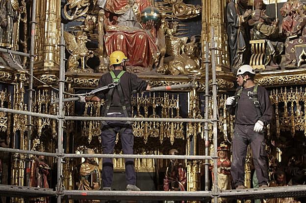 Los operarios comenzando a cubrir de andamios el retablo mayor. 