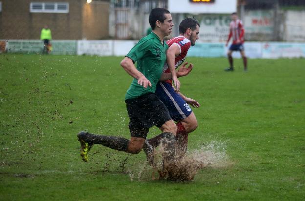 Dos jugadores forcejean para tratar de llegar al balón. 