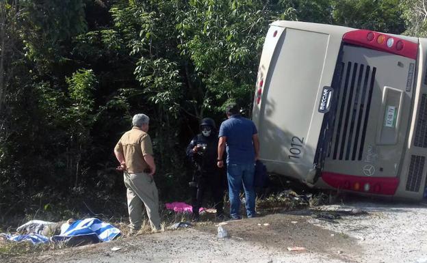 Dos hombres observan el autobús accidentado.