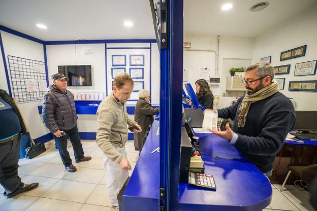 Un lotero atiende a un cliente en la administración número 2 de Llanes. 