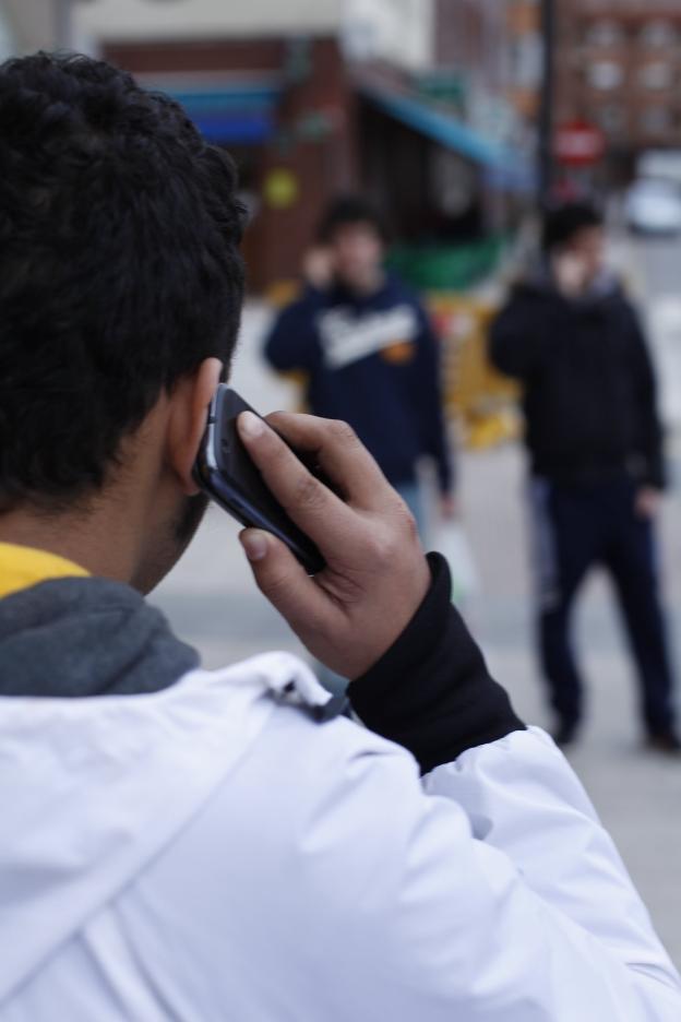 Un joven escucha una llamada en su teléfono móvil. 
