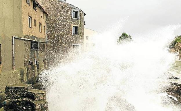Llanes. Una ola rompe junto a unas viviendas próximas a la plaza del Fuerte.