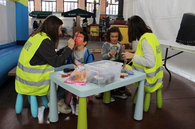 Las monitoras de Actívate Ocio pintan la cara a dos niños en uno de los talleres. 