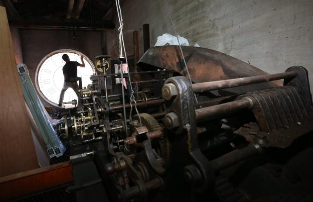 Un trabajador afina la maquinaria del reloj del Ayuntamiento de Avilés. 
