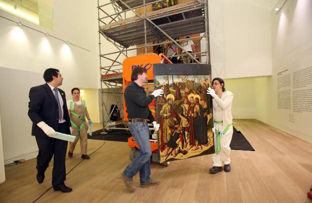 Los operarios, con una de las tablas que conforman el retablo, que comenzó a instalarse ayer. 