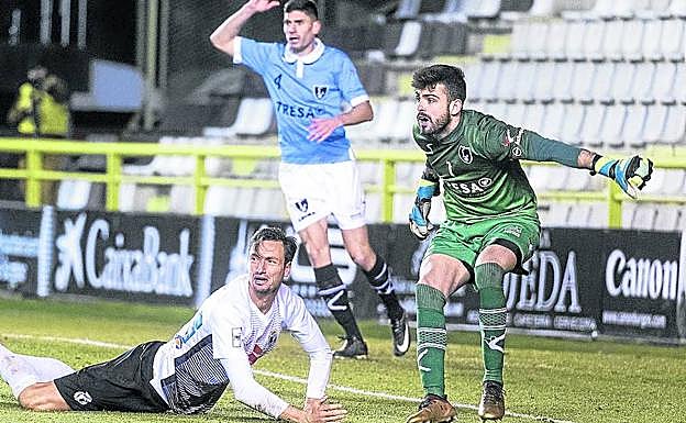 El guardameta Tejero y el defensa Mendi, con un rival, en el suelo.