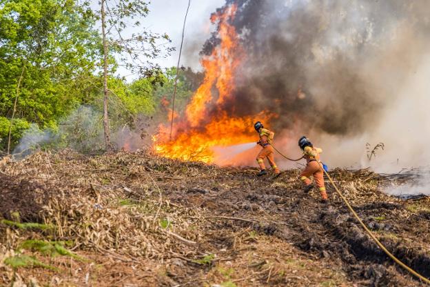 Dos bomberos tratan de sofocar las llamas de uno de los muchos incendios registrados en los montes del concejo de Llanes durante la jornada del 19 de abril de 2017. 