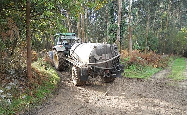 n tractor arrastra un depósito de purines por un monte asturiano. 