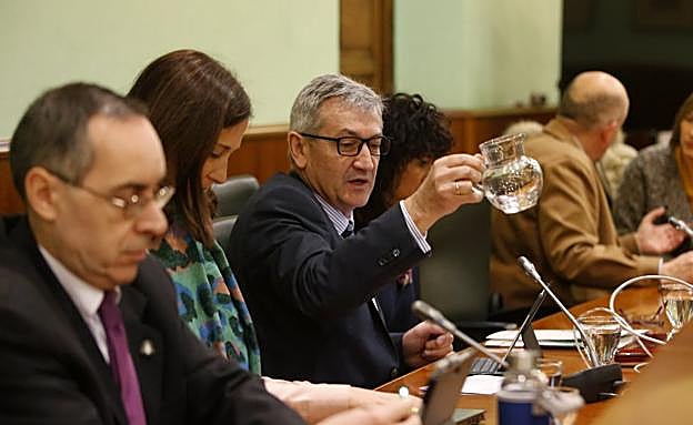 El rector, Santiago García Granda, se sirve agua antes de comenzar el Consejo de Gobierno. 