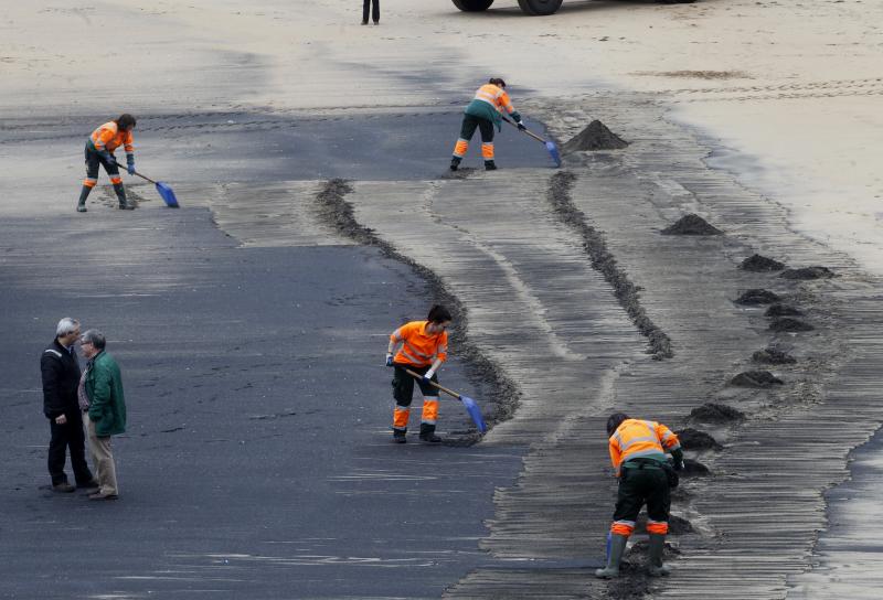 Operarios de Emulsa han iniciado las labores de limpieza de la mancha de carbón aparecida este domingo en la playa de San Lorenzo.