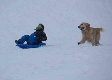 Imagen secundaria 1 - Arriba, la nieve en Sotres. Abajo a la izquierda, un niño en trineo; a la derecha, un hombre practicando snowboarding.