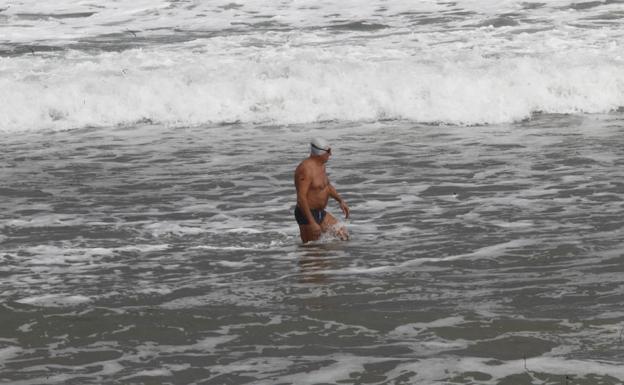 Imagen. Un 'valiente' se baña en la playa de San Lorenzo pese a las bajas temperaturas.