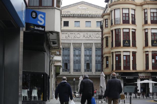 Tres personas se dirigen por la calle Menén Pérez en dirección al antiguo Teatro Arango. 