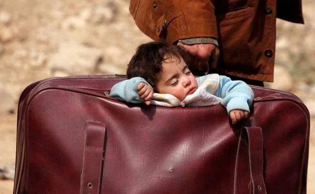 Un niño duerme en una maleta, en Guta, Siria.