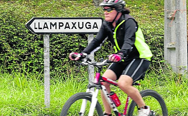 Una ciclista delante de la señal a Llampaxuga.
