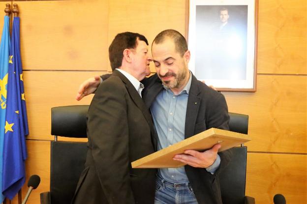 El cronista oficial de Lugones, José Antonio Coppen, recibe una placa conmemorativa de manos del alcalde, Ángel García. 