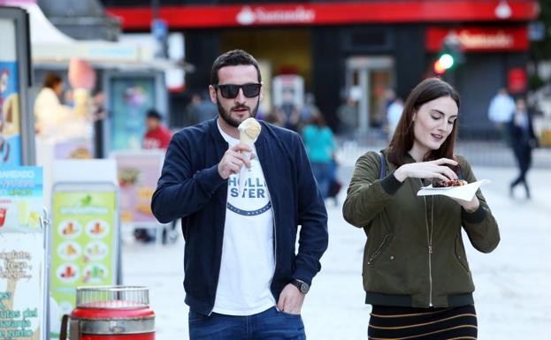 Imagen. Dos jóvenes disfrutan de sendos helados en el centro de Oviedo.