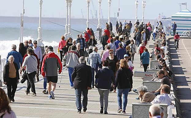 Gente paseando en el Muro de Gijón.