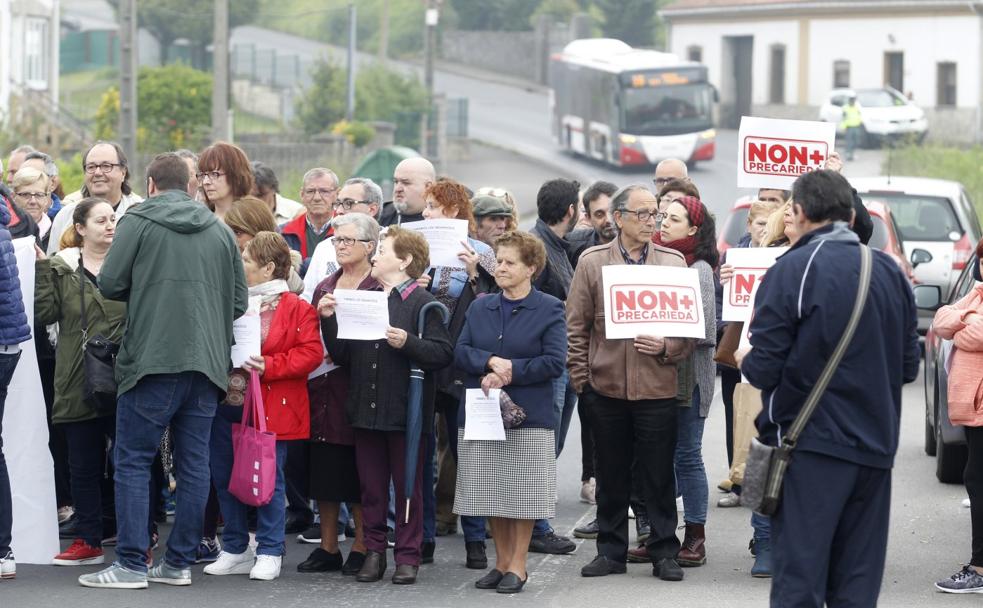 En primer plano, algunos de los vecinos que participaron en la protesta. Al fondo, el autobús de la línea 16, uno de los damnificados por el corte de la AS-248 a su paso por el llagar El Fugitivo, donde esperó pacientemente a que los vecinos finalizasen con el corte. 
