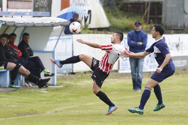 El atacante del Siero Cris lucha por hacerse con la posesión del balón perseguido por el lateral marinista Borja Álvarez. 