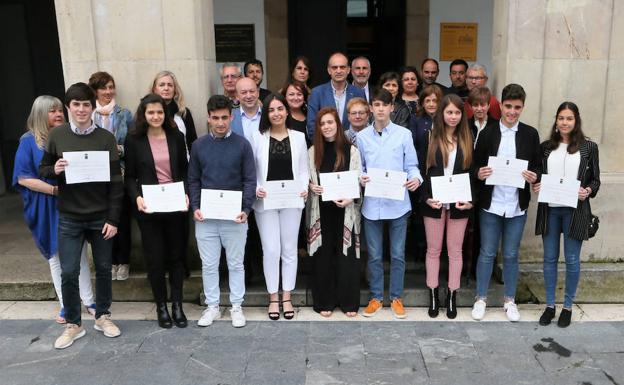 Los nueve alumnos premiados posando ayer con los diplomas junto a sus padres y los representantes de los tres institutos. 