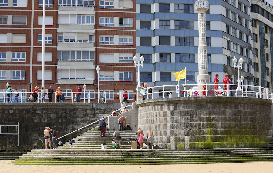 Las banderas amarilla y verde que luce la playa y la buena temperatura ya ha animado a algunas personas a pegarse un baño en el Cantábrico. 