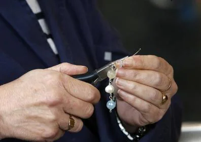 Imagen secundaria 1 - Joyería. A la derecha Ángel José Hidalgo en el taller de joyería del CAI.Elaboración de una pulsera que después venderán en el paseo de los Álamos y cuyos beneficios irán destinados a la organización de un viaje. 