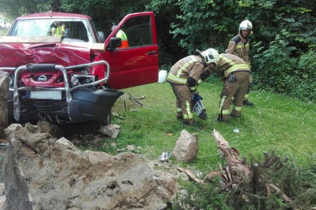 Los bomberos junto al vehículo accidentado al lado de la fuente de Malpica. 