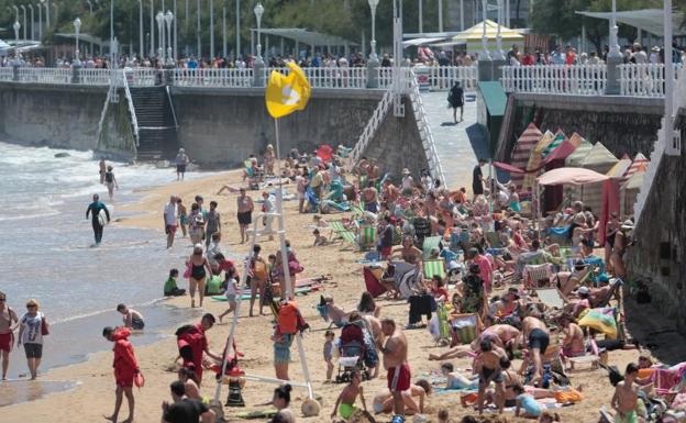 Miles de personas disfrutan del sol en la playa de San Lorenzo, en Gijón. 