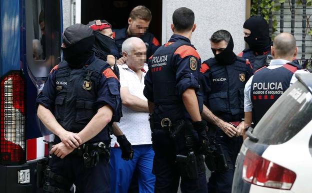 Los Mossos d'Esquadra trasladan del domicilio en la calle Torrent d'en Grau de Badalona (Barcelona), a uno de los detenidos durante la operación policial. 