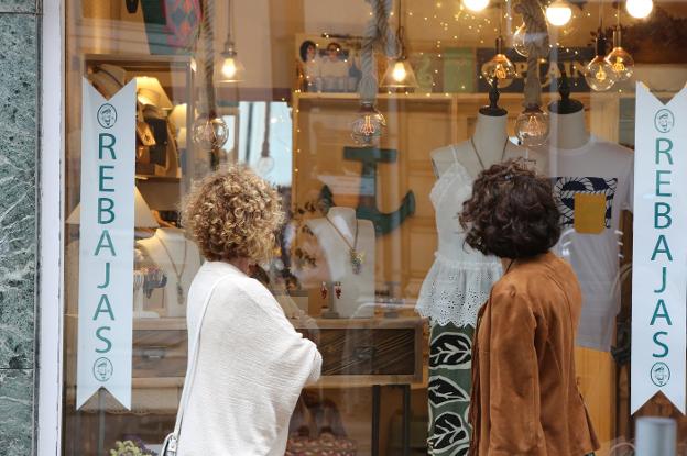 Dos mujeres se interesan por los productos de un comercio en rebajas en el centro de Avilés. 