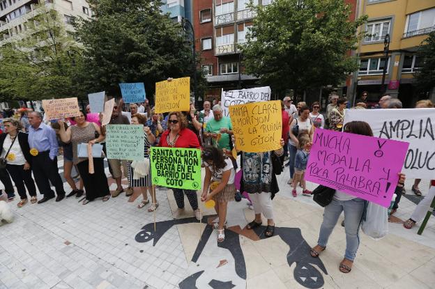 Vecinos del barrio de El Coto protestan con pancartas y silbatos delante del teatro Jovellanos. 