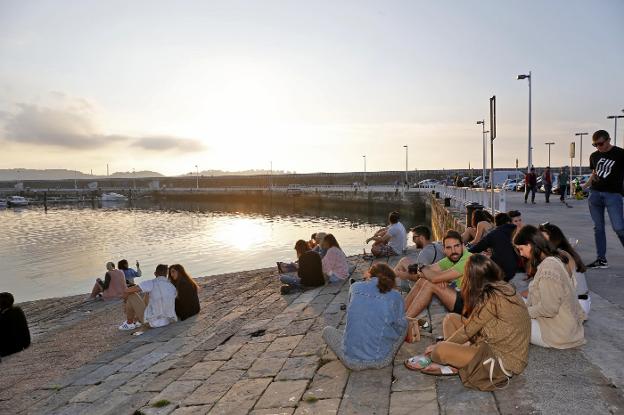 Jóvenes disfrutan del atardecer en la rampa de la antigua rula gijonesa tras una jornada de intermitentes lluvias. 