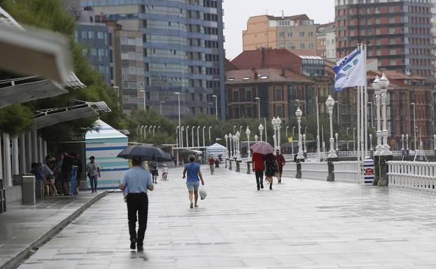 Los más previsores alternaron las camisetas de manga corta con los paraguas en Gijón. 