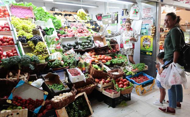 Una mujer en un puesto de frutas y verduras en Gijón.