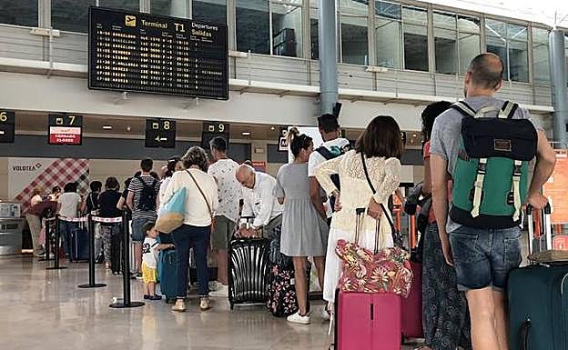 Pasajeros del vuelo cancelado hacen cola en el aeropuerto de Asturias. 