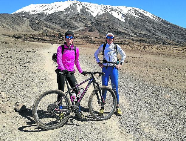 Ruth Moll, con su bicicleta, junto a Ruth Gómez, con el Kilimanjaro al fondo. 
