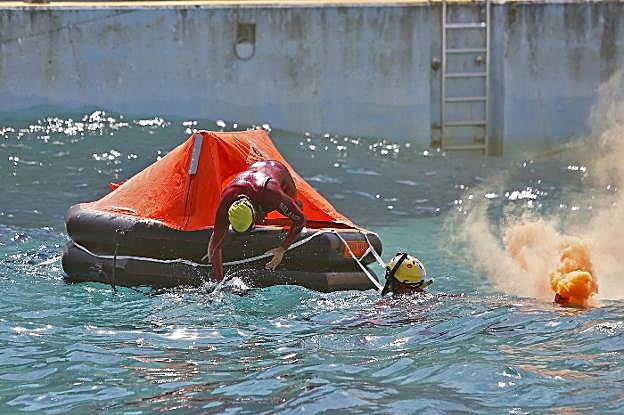 Los aspirantes a rescatadores marítimos deben subirse y bajarse de una balsa azotada por las olas. 