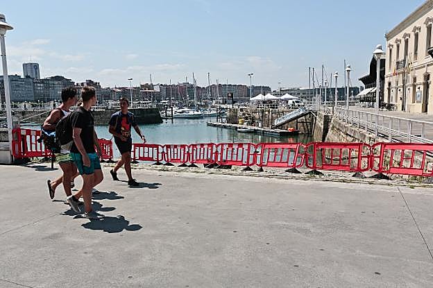 Un grupo de jóvenes pasa delante del vallado que cierra el acceso a las rampas situadas frente a la Cuesta del Cholo, para evitar que se dejen allí desperdicios. 
