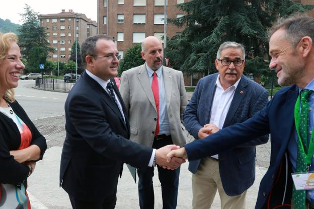 El consejero de Industria, Isaac Pola, estrecha la mano de Eduardo Álvarez, uno de los organizadores del congreso de energías renovables de Mieres, en presencia del vicerrector de Extensión Universitaria, Francisco José Borge, y el alcalde de Mieres, Aníbal Vázquez. 