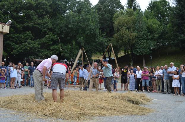 Arriba, dos parejas mallan el centeno en el recinto ferial del Foxo. Sobre estas líneas, la máquina que separa la paja del grano. 