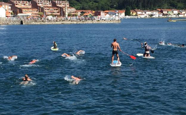 Un grupo de bañistas nada desde San Esteban de Pravia hasta San Juan de La Arena.