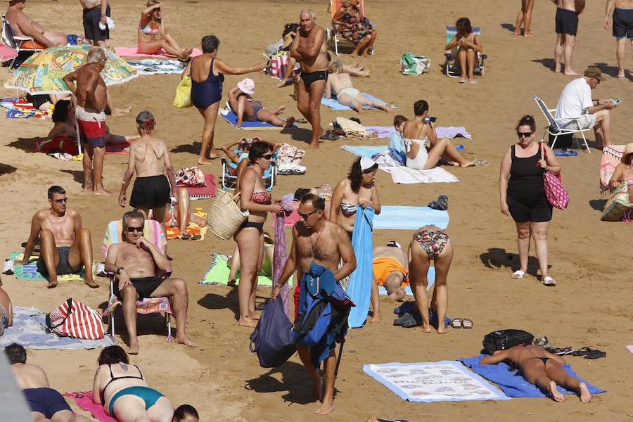 El sol y el calor anunciados para este fin desemana han llenado las playas de Asturias. En San Lorenzo, por ejemplo, miles de personas disfrutan del arenal y del paseo del Muro.