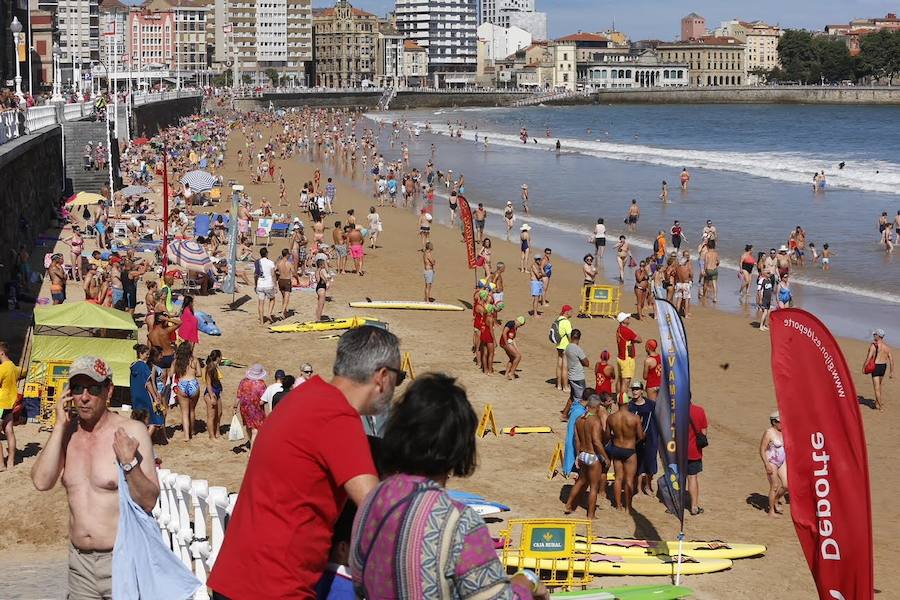 El sol y el calor anunciados para este fin desemana han llenado las playas de Asturias. En San Lorenzo, por ejemplo, miles de personas disfrutan del arenal y del paseo del Muro.