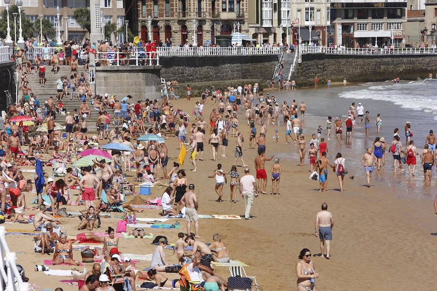 El sol y el calor anunciados para este fin desemana han llenado las playas de Asturias. En San Lorenzo, por ejemplo, miles de personas disfrutan del arenal y del paseo del Muro.