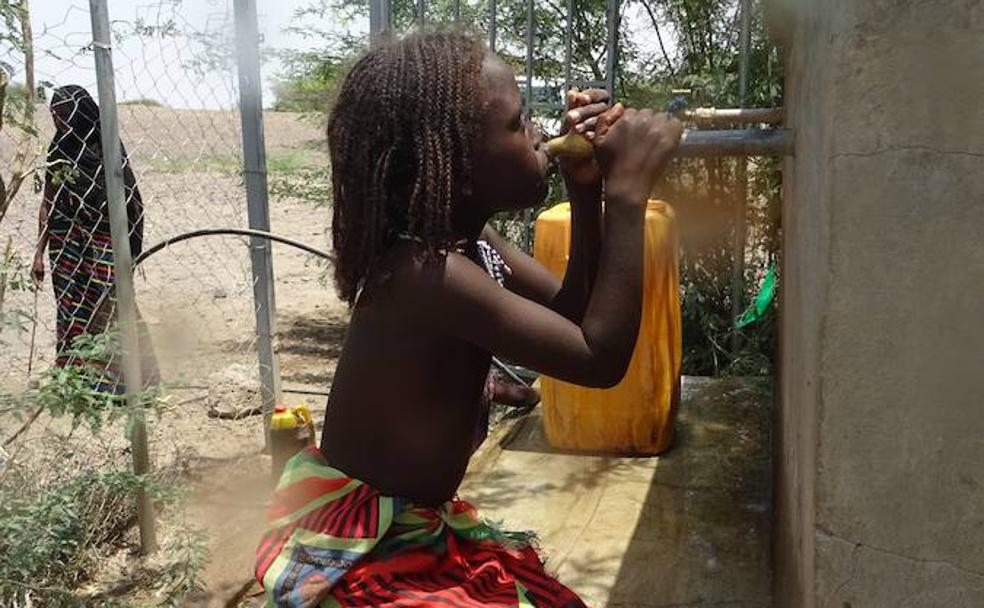 Una niña afarí bebe agua directamente de uno de los suministros instalados por Amref. 