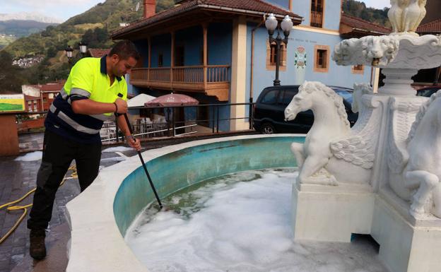 Un operario limpia la fuente.