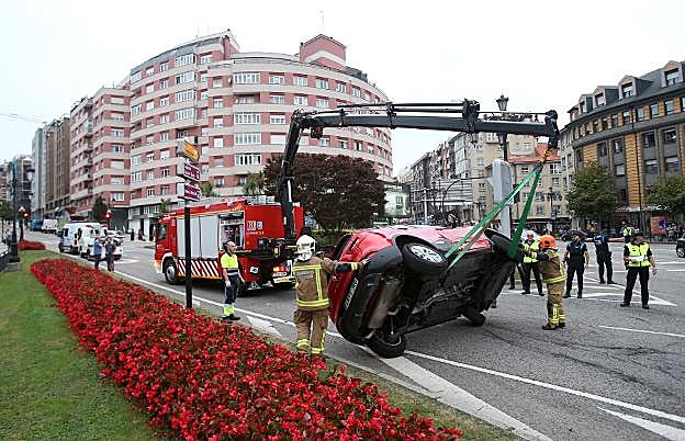Los Bomberos levanta el vehículo siniestrado en la plaza de la Cruz Roja este viernes. 